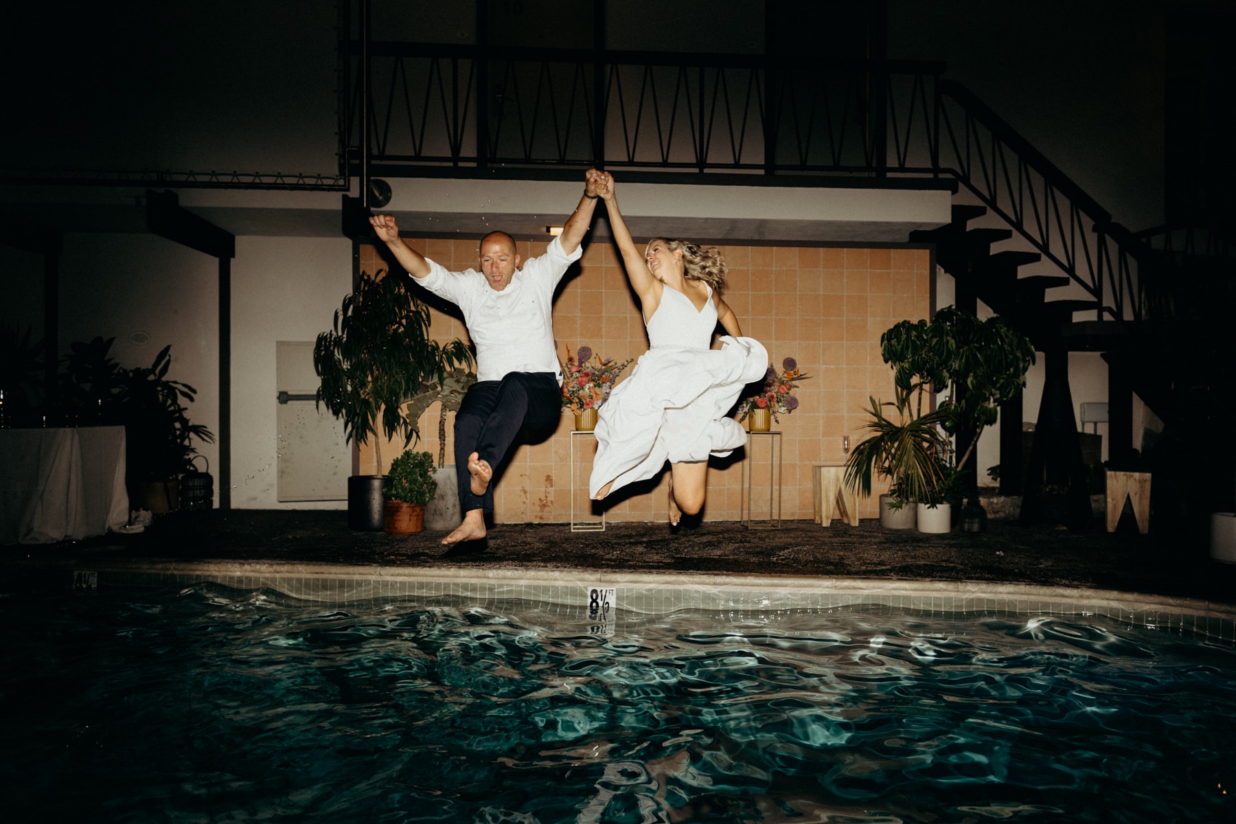 wedding couple jumping in the pool at the pearl